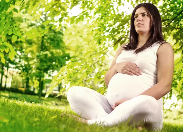 Femme enceinte assise sur l'herbe — Photo