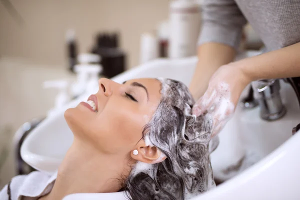 Jovem mulher lavando o cabelo no salão — Fotografia de Stock