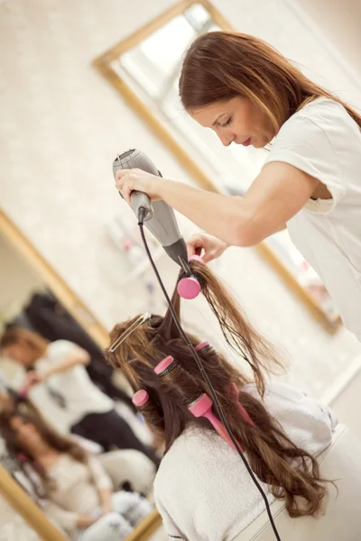 Femme coiffeuse séchant les cheveux de femme — Photo