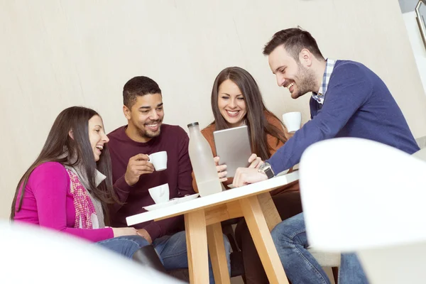 Amigos sonriendo y sentados en una cafetería, hablando y bebiendo — Foto de Stock