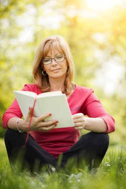 Parkta kitap okuyan kadın.