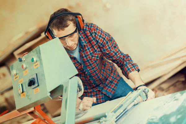 Carpintero con sierra circular automática. Tiene gafas protectoras. — Foto de Stock