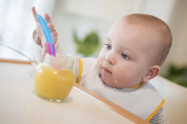 Um bebê agarrando um pote de comida — Fotografia de Stock