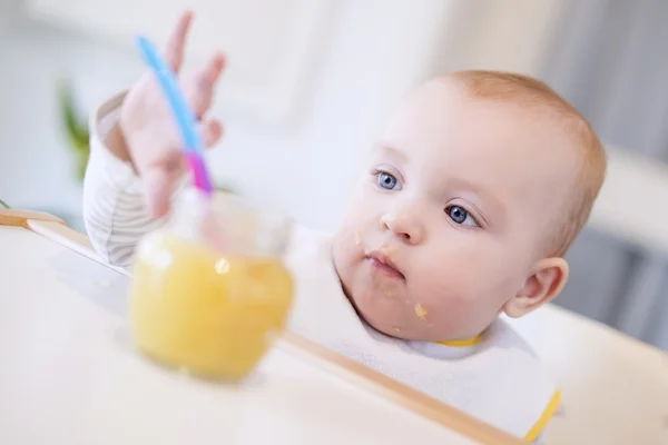 En baby som roffar åt sig en burk mat — Stockfoto
