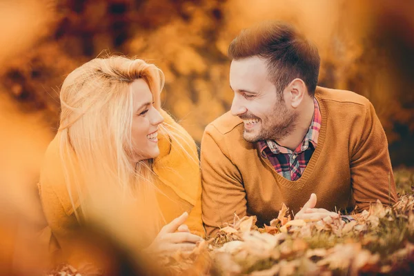 Vackra par liggande i parken bland blad — Stockfoto