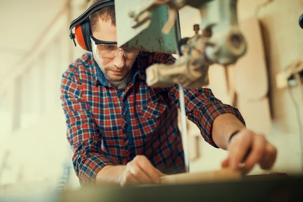 Nahaufnahme eines jungen Tischlers bei der Arbeit. Er benutzt eine Bandsäge. — Stockfoto