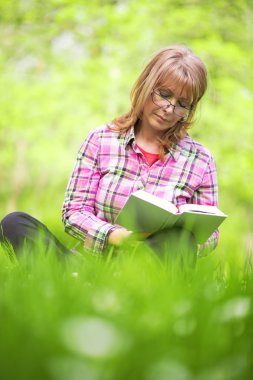 Dışarıda kitap okuyan kadın.