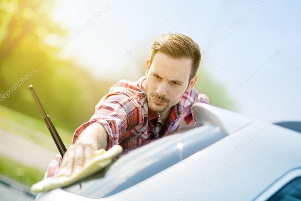 Young man cleaning his car