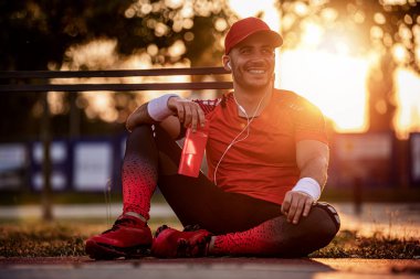 Sporcu adam antrenmandan sonra şişeden su içiyor ve dinleniyor..