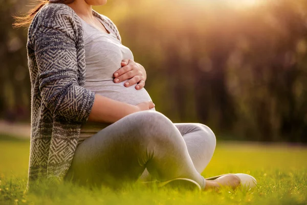 Крупный План Беременной Женщины Сидящей Парке Держащей Живот — стоковое фото