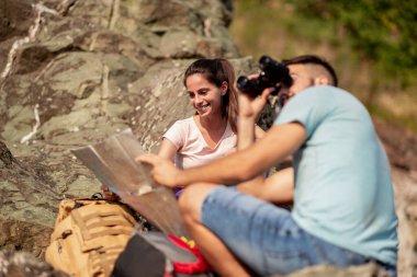 Genç çift, dağda otururken dürbünle bakıyor. Doğa, yürüyüş ve yaşam tarzı konsepti.