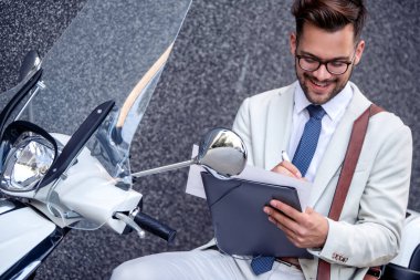 Çalışırken motosiklette oturan yakışıklı genç iş adamı..