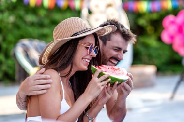 Yüzme havuzunda karpuz yiyen genç çift. Mutluluk, neşe, tatil, plaj ve yaz konsepti..