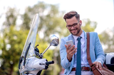 Çekici genç iş adamı cep telefonuna bakıyor ve gülümsüyor. İş, insan ve yaşam tarzı kavramı.