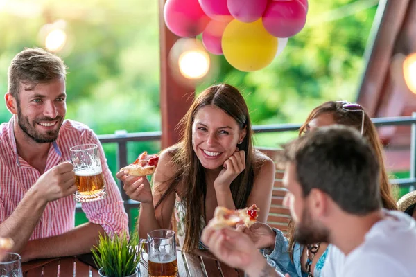 Young people having fun at party with delicious pizza.