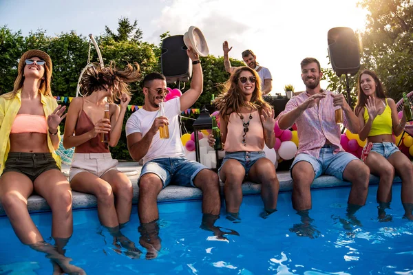 Enjoying pool party with friends. Group of friends having party by swimming pool.