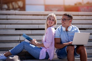 Şehirde dizüstü bilgisayar kullanan genç üniversite öğrencileri. Dışarıda dizüstü bilgisayarı olan öğrenciler..