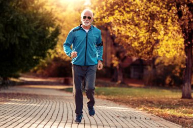 Kıdemli koşucu sonbahar parkında koşuyor.