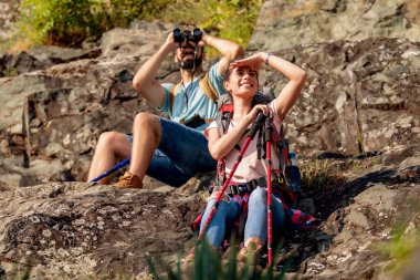 Genç çift dağdaki dürbünden bakıyor. Yürüyüş ve yaşam tarzı konsepti.