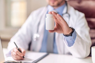Doktor, ofisteki masaüstünde bir kutu hap gösteriyor. Sağlık, tıbbi ve eczane konsepti.
