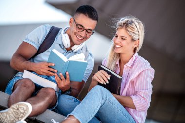 Merdivenlerde kitaplarla oturan genç öğrencilerin fotoğrafı. Eğitim, insanlar, üniversite ve yaşam tarzı konsepti.