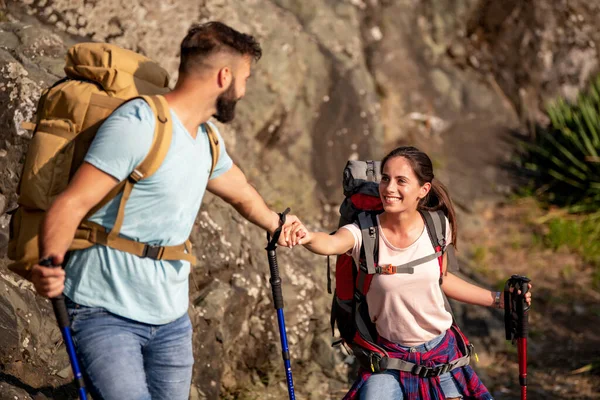 Hikers with backpacks and hiking sticks clim the mountain.