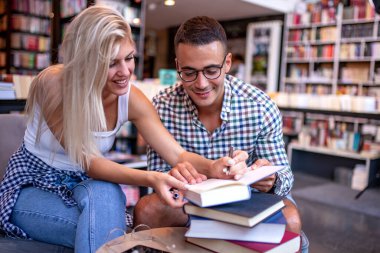 Kütüphanede kitap arayan genç bir çift. Eğitim, öğrenme ve yaşam tarzı kavramı.