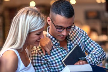 Kütüphanede kitap arayan genç bir çift. Eğitim, öğrenme ve yaşam tarzı kavramı.