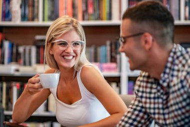 Eğitim, flört, üniversite ve yaşam tarzı konsepti. Birkaç öğrenci kütüphanede okuyor ve kahve içiyor..