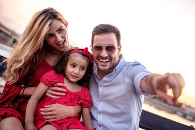 Parktaki bankta oturan genç bir aile..