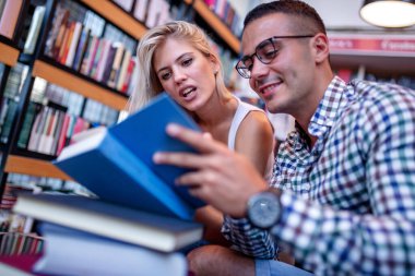 Kütüphanede kitap arayan genç bir çift. Eğitim, öğrenme ve yaşam tarzı kavramı.