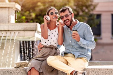 Sevgili çiftin portresi cep telefonu kullanıyor ve sokakta müzik dinliyor..