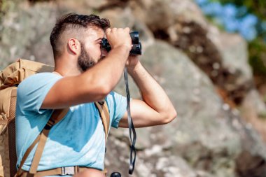 Dürbünle dağdaki genç adam. Doğa, insanlar ve yaşam tarzı kavramı.