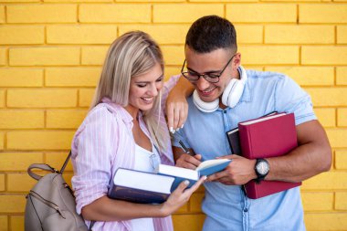 Kollarında kitap olan öğrenciler. Eğlenir ve konuşurlar. Eğitim, flört, üniversite ve yaşam tarzı kavramı.