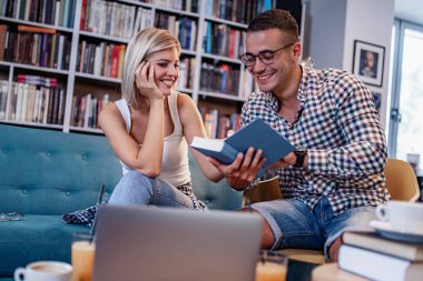 Eğitim, flört, üniversite, ilişkiler, yaşam tarzı konsepti - Uluslararası öğrencilerin çiftleri kütüphanede okuyor.