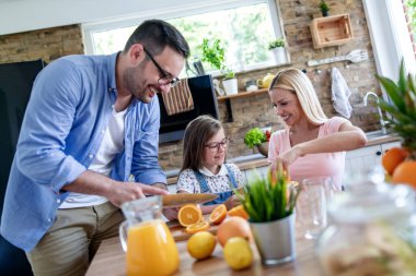 Anne, baba ve kız evde taze portakal suyu yapıyorlar. Aile, aşk, yemek ve içki konsepti.