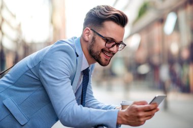 Genç işadamı mola veriyor, kahve içiyor ve cep telefonu kullanıyor..