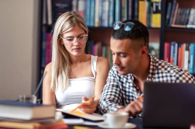 Eğitim, flört, üniversite, ilişkiler, yaşam tarzı konsepti - Uluslararası öğrencilerin çiftleri kütüphanede okuyor.