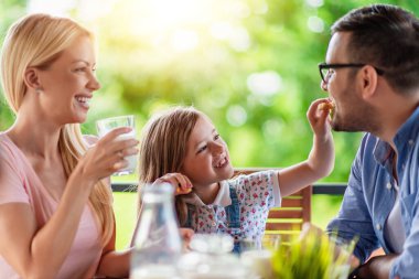 Üç kişilik aile terasta kahvaltı yapar. Aile, yemek ve yaşam tarzı kavramı..