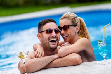 Güzel bir çift havuz başında eğleniyor, kokteyl içiyor. Aşk, insanlar, tatil ve yaşam tarzı kavramı.