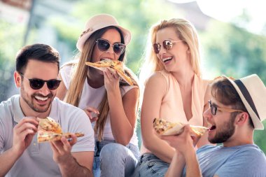 Arkadaşlar pizza yiyor, dışarıda eğleniyor. İnsanlar, eğlence, yemek ve yaşam tarzı konsepti..