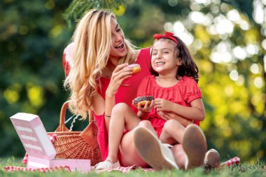 Çekici anne ve kızı parkta donut yerken eğleniyorlar..