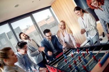 İş adamları birlikte harika vakit geçiriyorlar. Meslektaşlar modern ofiste masa futbolu oynuyorlar..