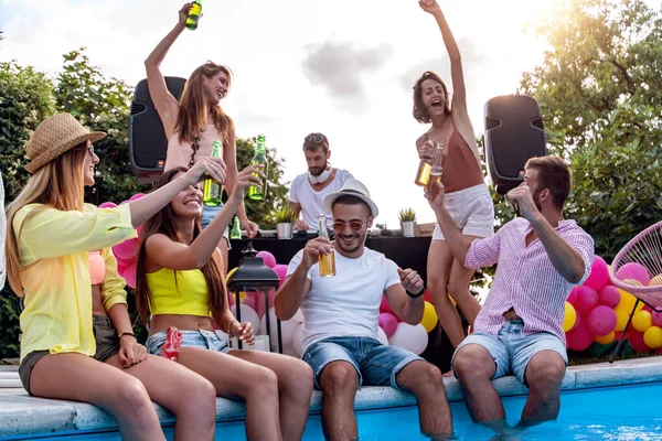 Enjoying pool party with friends. Group of friends having party by swimming pool.