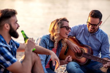 Arkadaşlarımla harika vakit geçiriyorum. Gençler sahilde birlikte oturuyorlar..