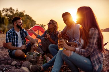 Bir grup arkadaş gün batımında oturup müzik dinliyorlar..