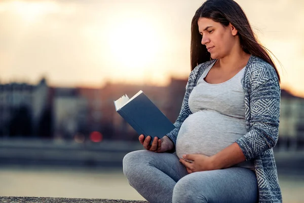 妊娠中の女性が川でリラックスして本を読んで — ストック写真
