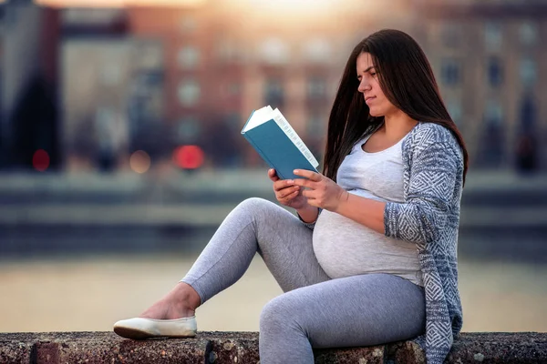 妊娠中の女性が川でリラックスして本を読んで — ストック写真