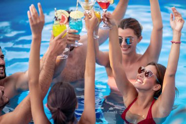 Bir grup arkadaş havuzda parti veriyor, kokteyl içiyor ve birlikte eğleniyorlar..
