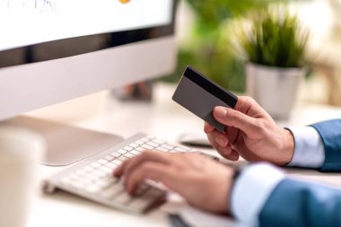 Erkek işadamı ofiste bilgisayarda çalışıyor. Kredi kartı gösteriliyor. İş ve yaşam tarzı kavramı.